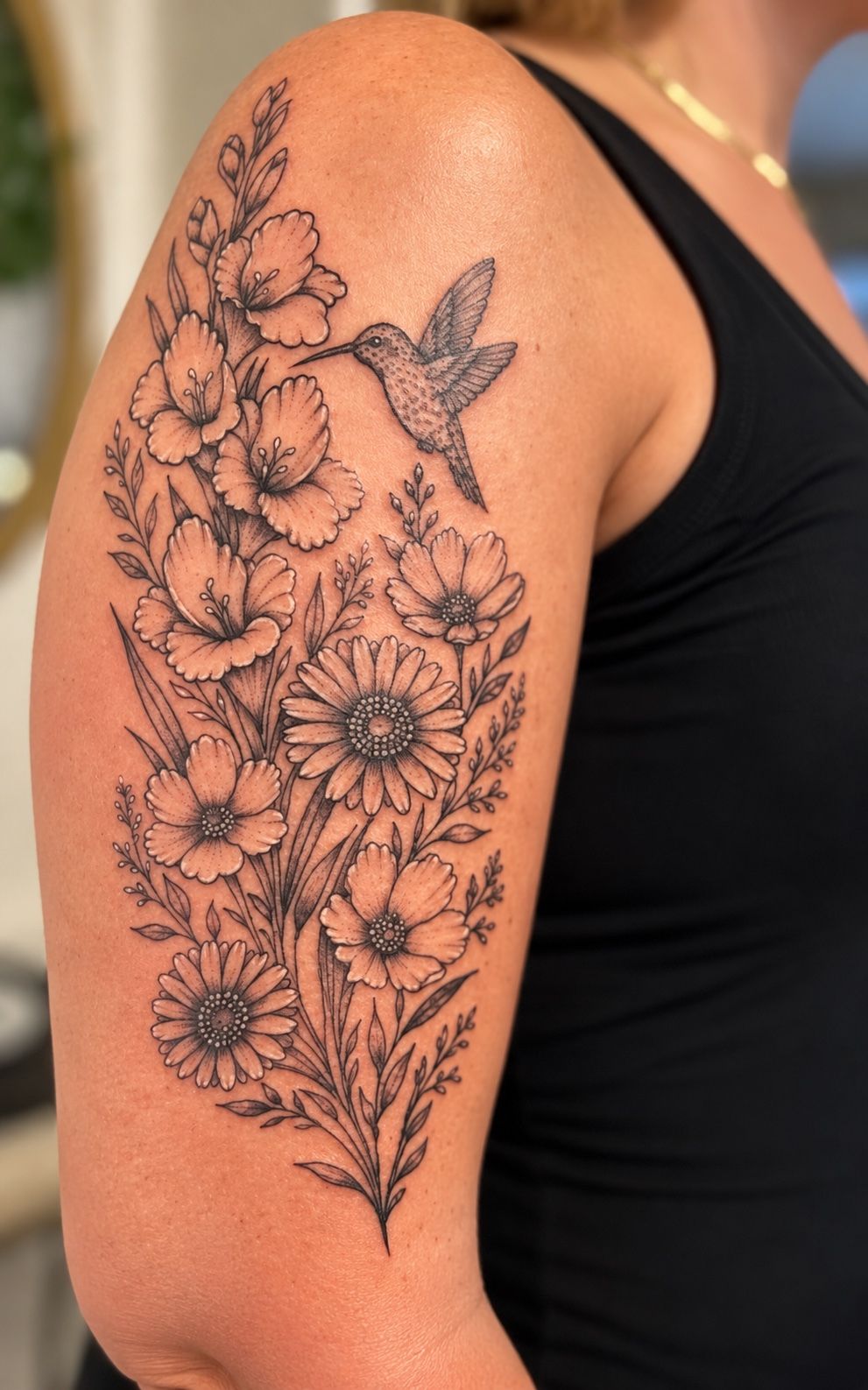 Fine line hummingbird with wildflowers and daisies on the upper arm